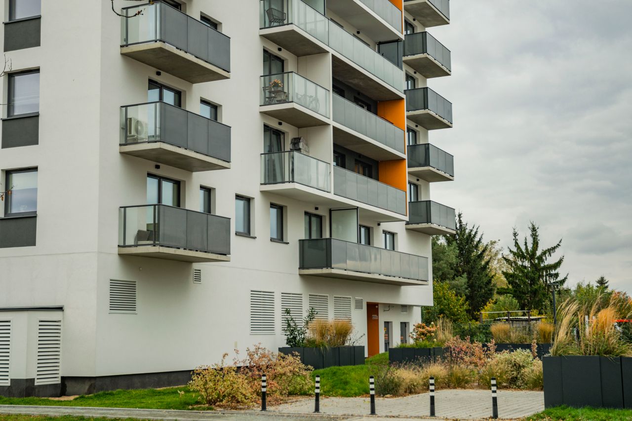 Home Contemporary apartment complex featuring glass balconies and landscaped surroundings.