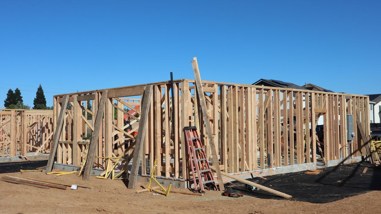 Services Framing stages of new home construction in sunny Elk Grove, California.